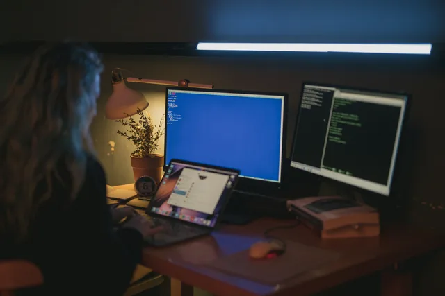 Woman using multiple screens for cybersecurity tasks in a cozy home office. Så får it-avdelningen kontroll över företagets SaaS-prenumerationer